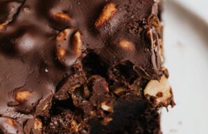 El Chocolate: El Dulce Tesoro que Conquistó al Mundo Close-up of a decadent chocolate brownie with nuts on a white plate.
